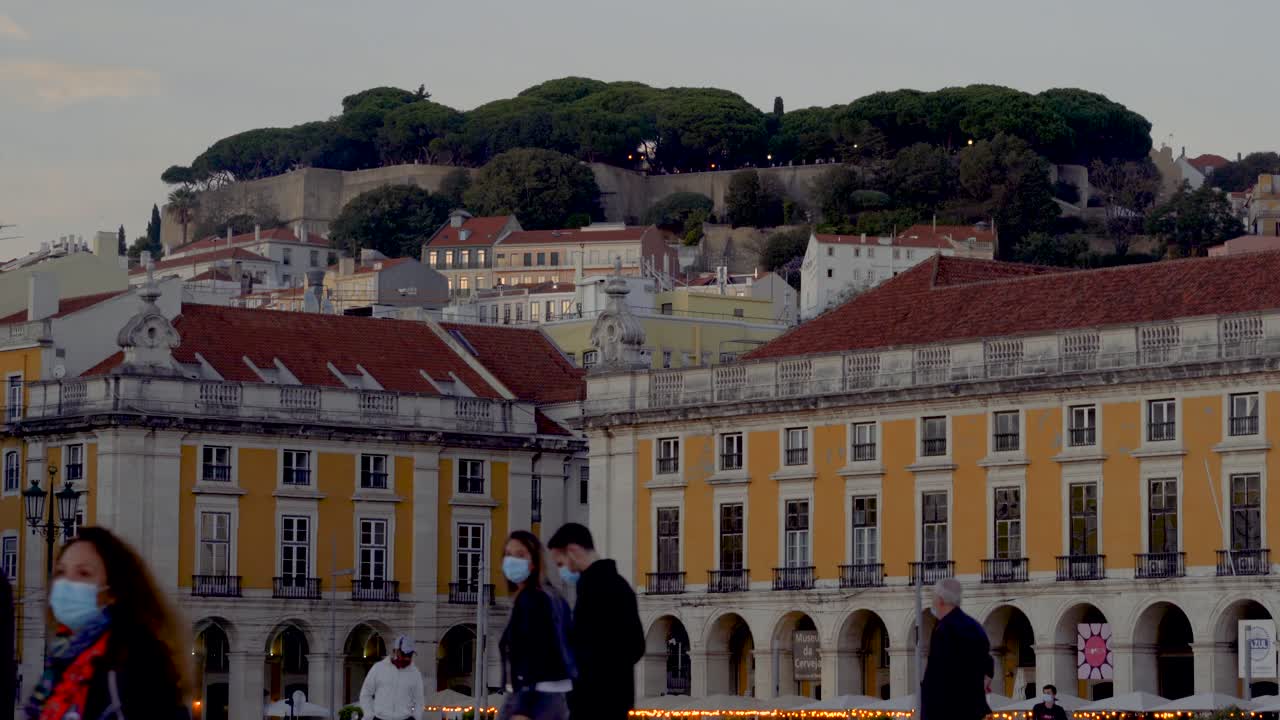 Strolling in Praça do Comercio, Lisbon, Portugal. Castelo de Sao Jorge in background. Beautiful centenary buildings.