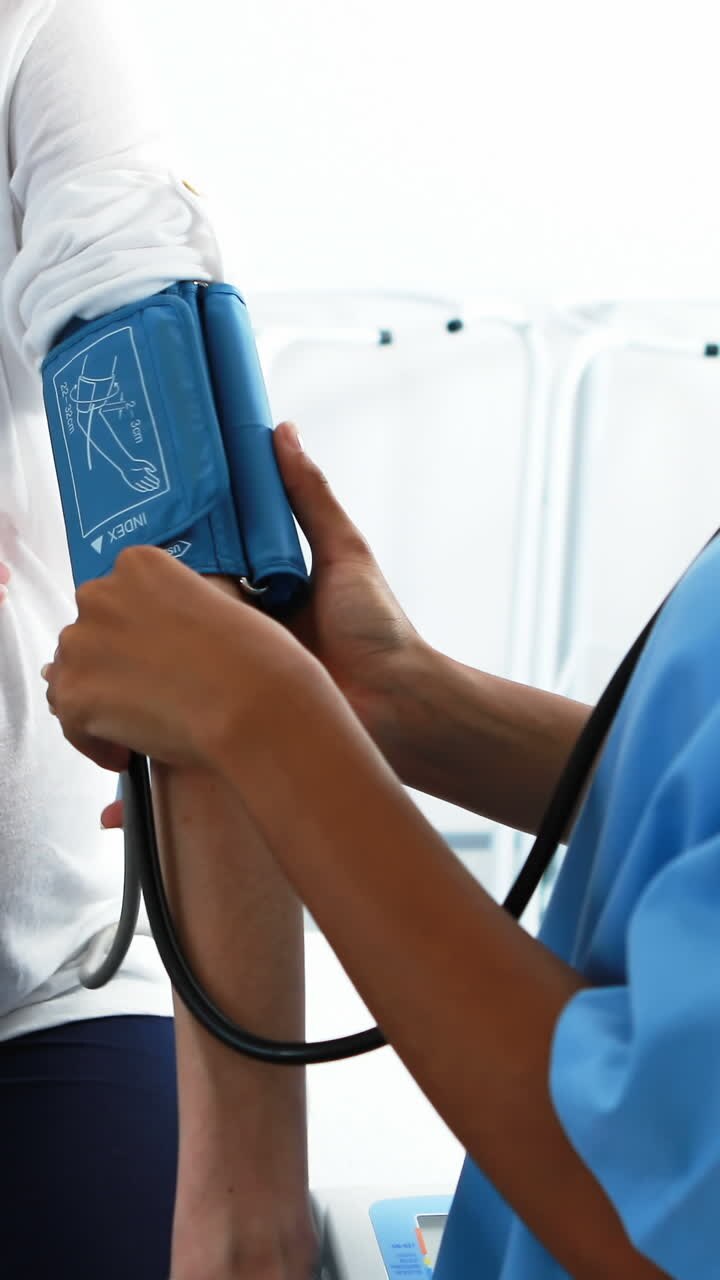 Mid section of doctor checking blood pressure of pregnant woman