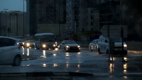 Cars driving through flooded street in Dubai, United Arab Emirates at night fall during winter