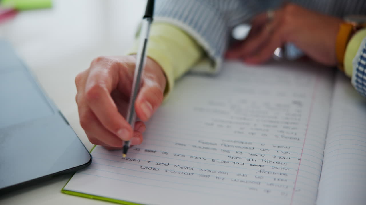 Person writing notes on a notebook with a pen