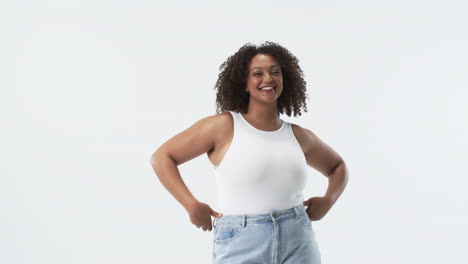 young biracial plus size woman with curly hair smiling and posing in studio