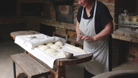 georgian baker rolling and shaping dough on table then pressed to stick on the wall of tone oven