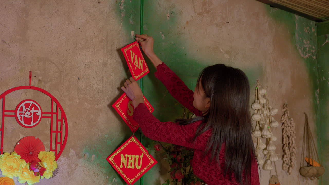 Chinese New Year celebration , housewife woman in traditional red dress preparing the house with decoration wearing red dress in China Asia