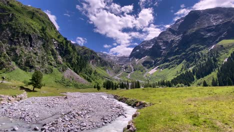 river with stones in the beautiful lüsens valley in austria with high mountains and blue sky in the background