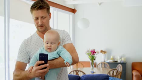 father and baby boy using mobile phone in living room 4k