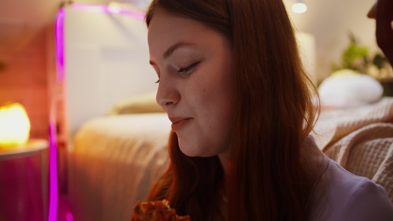 십대 소녀가 침실에서 피자를 먹고 있다