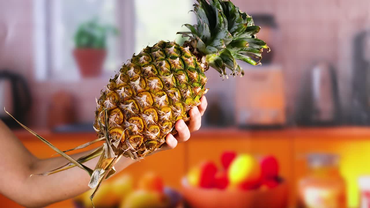 persona sosteniendo una piña en una cocina