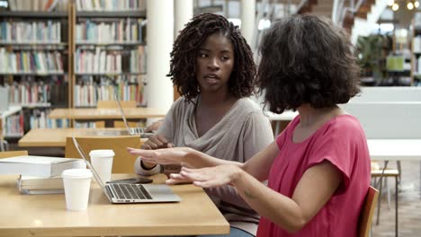 Side-view-of-focused-women-using-laptop-at-library