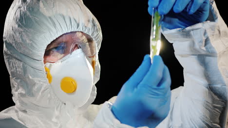 a researcher in a protective suit looks at a test tube with a plant sample