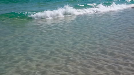 A serene beach scene captured from a low angle, showcasing gentle waves lapping the shore