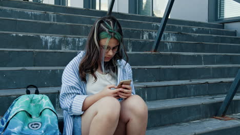 una adolescente en las escaleras con un teléfono inteligente