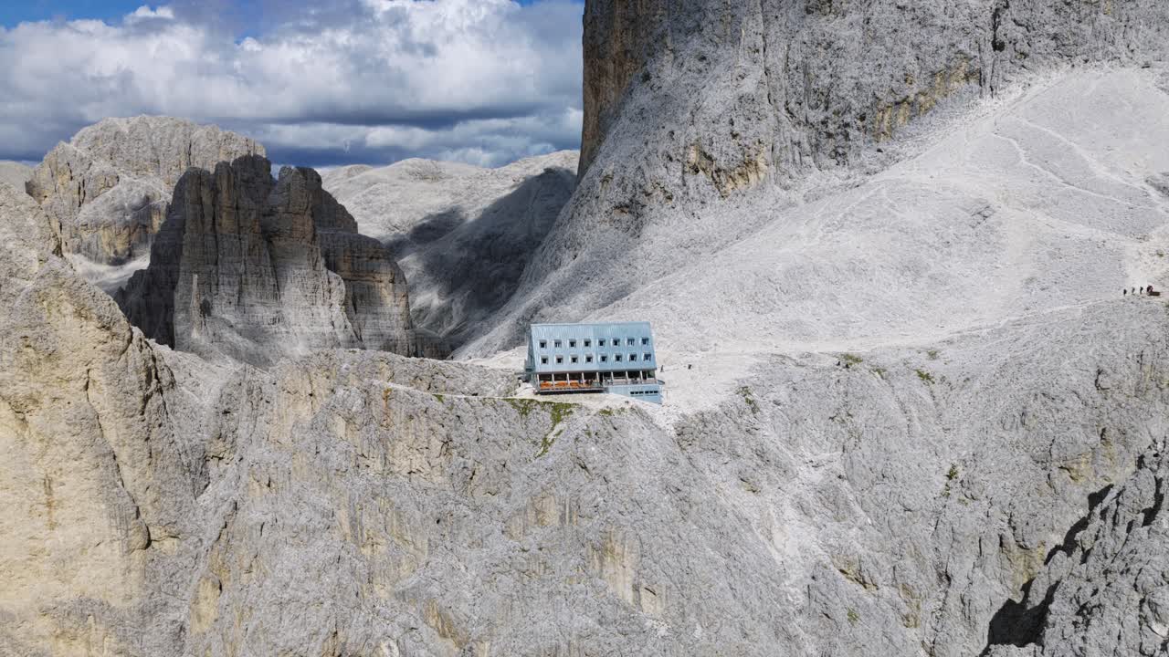 Vajolet refuge building on a rocky alpine mountain ridge against a blue sky