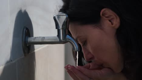 young woman drinks fresh water from a tap