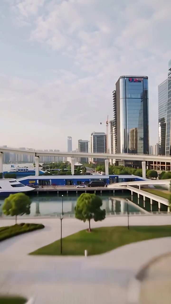 Vertical video: Moving aerial camera documenting high-rise with crane and blue cladding at marina