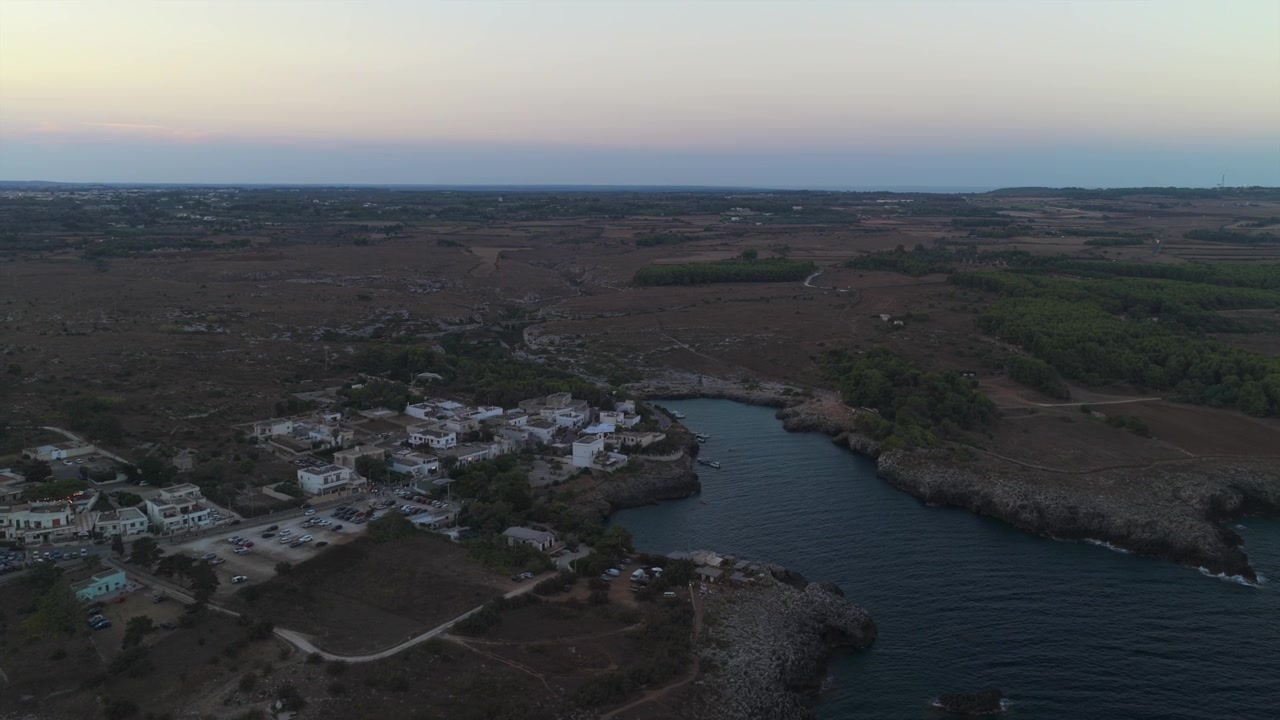 Riprese aeree che mostrano la splendida costa di Torre Sant'Andrea con le sue coste rocciose e un pittoresco villaggio bagnato dalle calde tonalità del crepuscolo