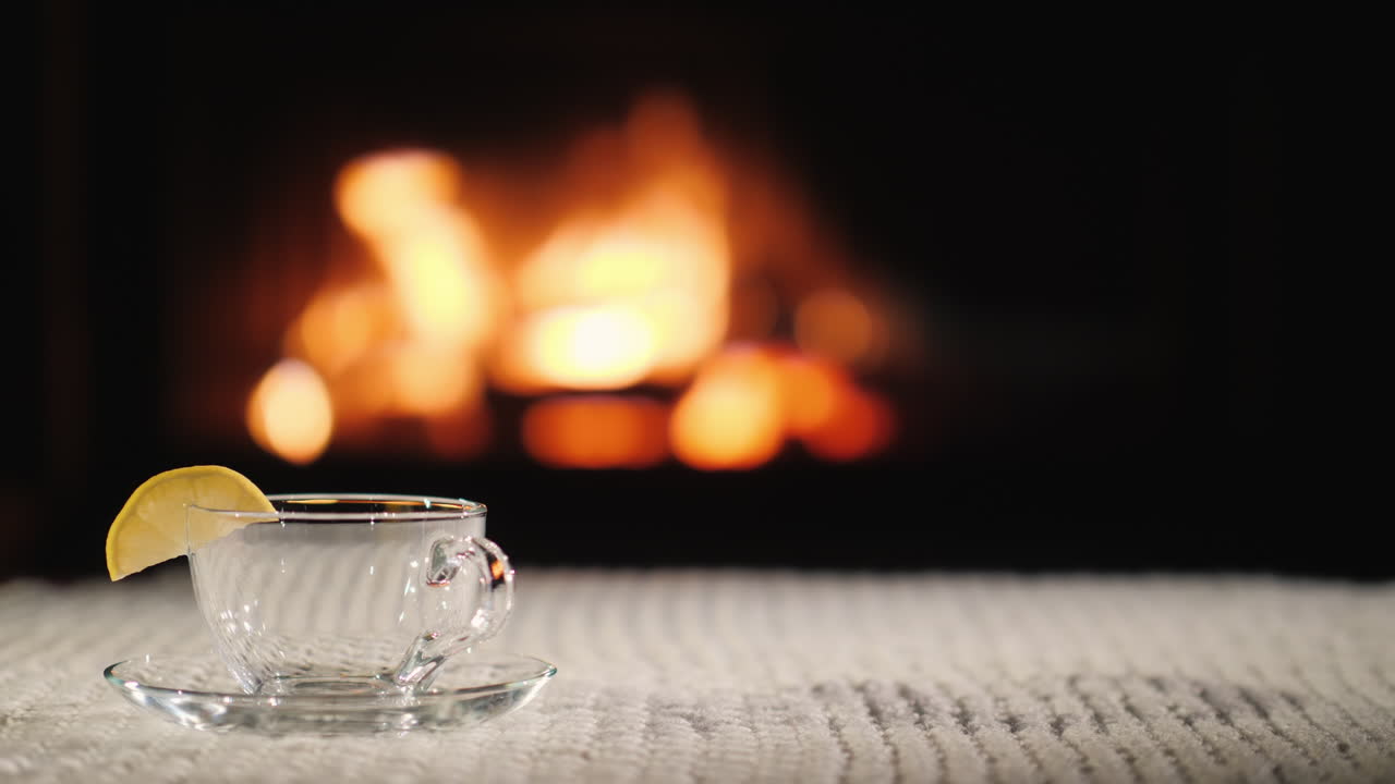 наливают чай в чашку на фоне камина чай в уютной обстановке