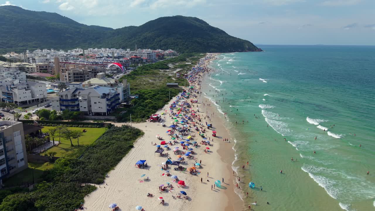 Atividade de parapente motorizado sobre praia e costa urbana nos Ingleses, acompanhamento aéreo panorâmico, Santa Catarina Florianópolis Brasil.