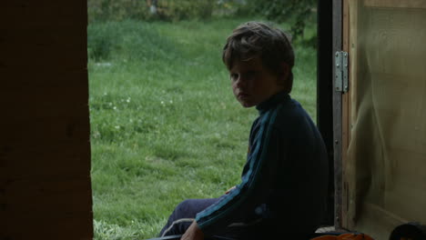 boy sitting by door in garden