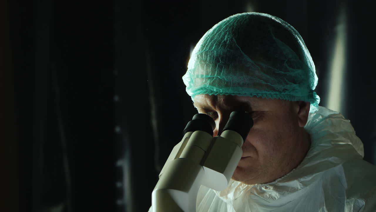 Researcher in viral lab works with microscope and laptop 1