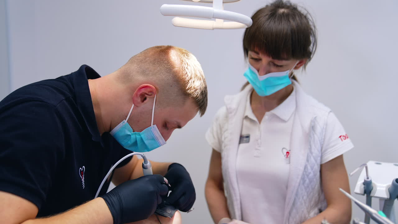 Dentista e assistente durante il lavoro di squadra. Il dentista controlla i denti di una paziente in una clinica dentale.