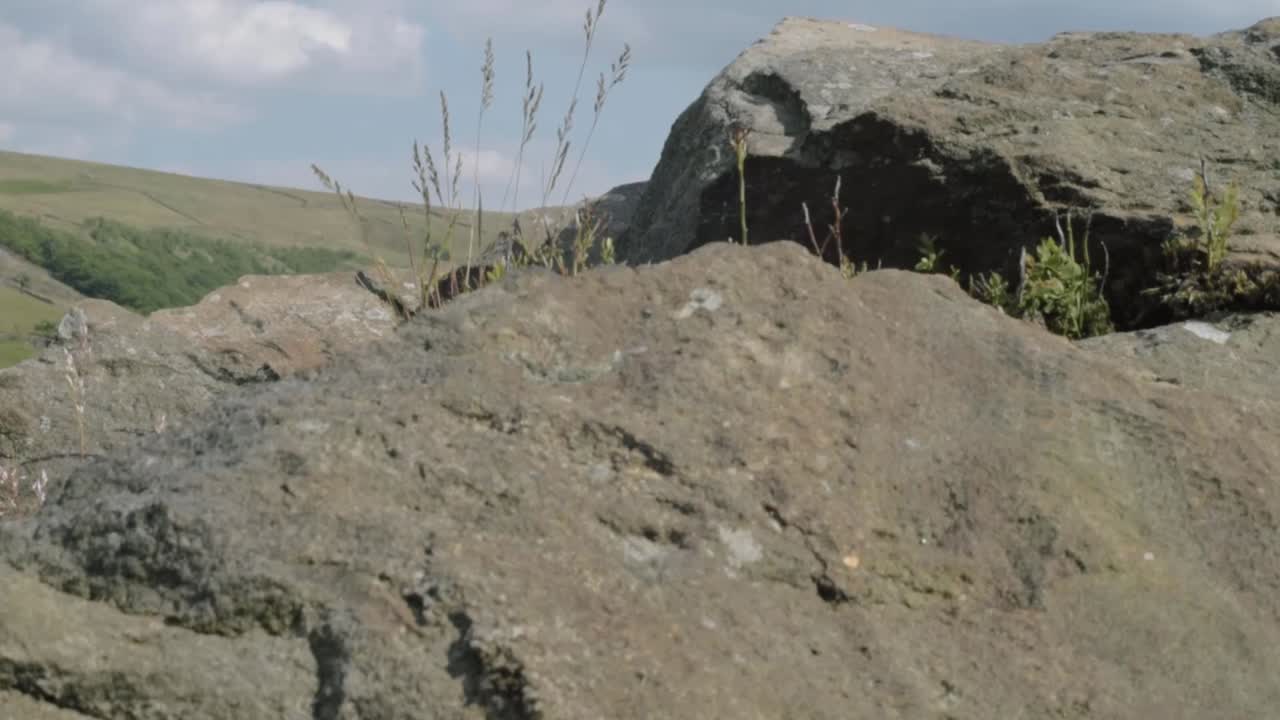 Rocky terrain revealing Butterley reservoir wide tilting shot