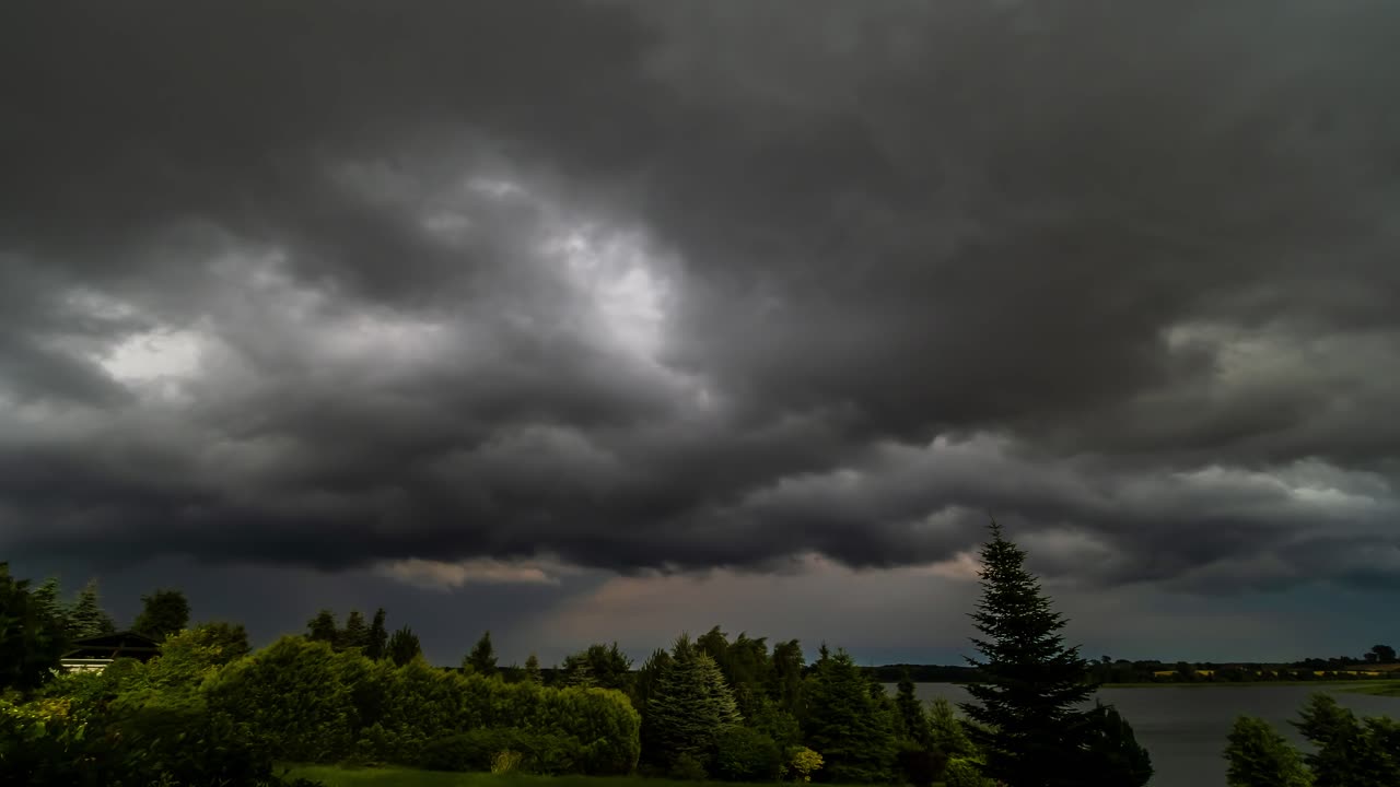 나무와 호수를 덮는 폭풍 구름의 시간 경과