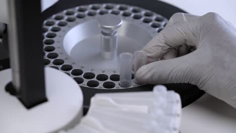 medical laboratory scientist with gloved hands puts the reaction tube into the chemistry analyzer