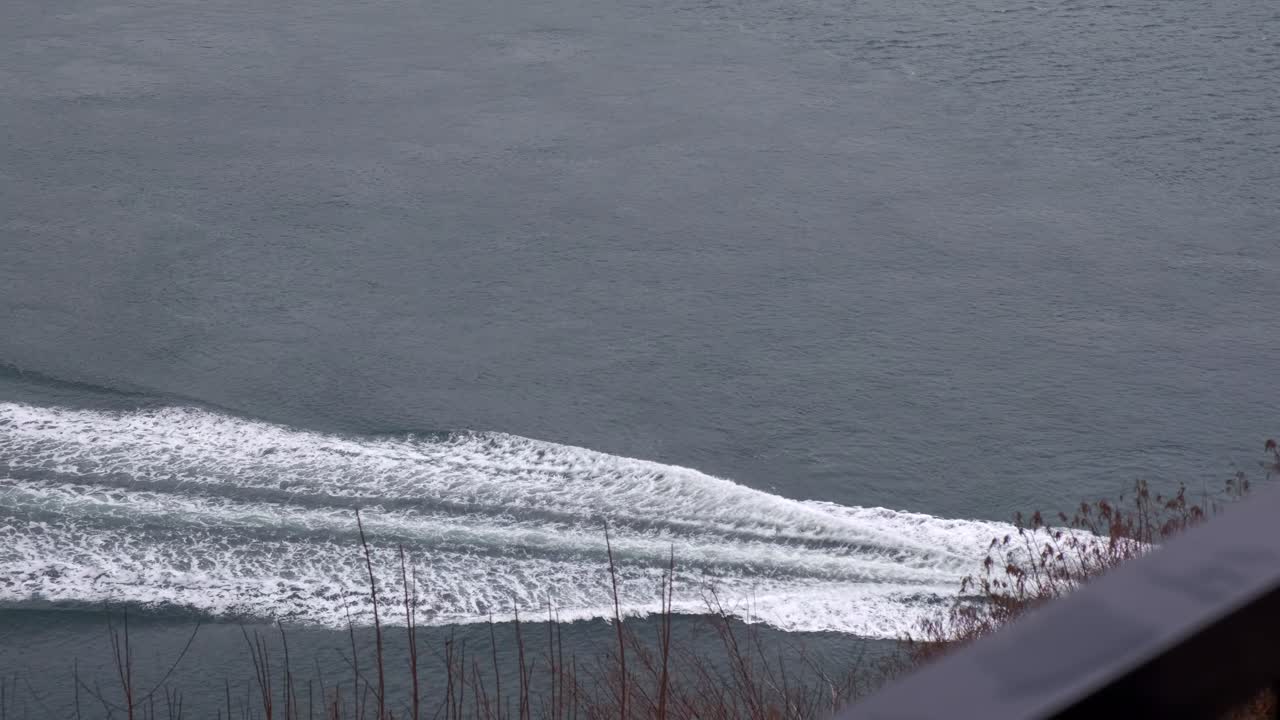 흐린 겨울날 잔잔한 바다를 순항하고 오른쪽에서 빠져나가는 작은 흰색 보트