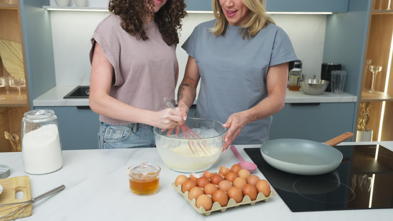 Happy women making a pastry recipe with eggs and strawberries. Slow motion