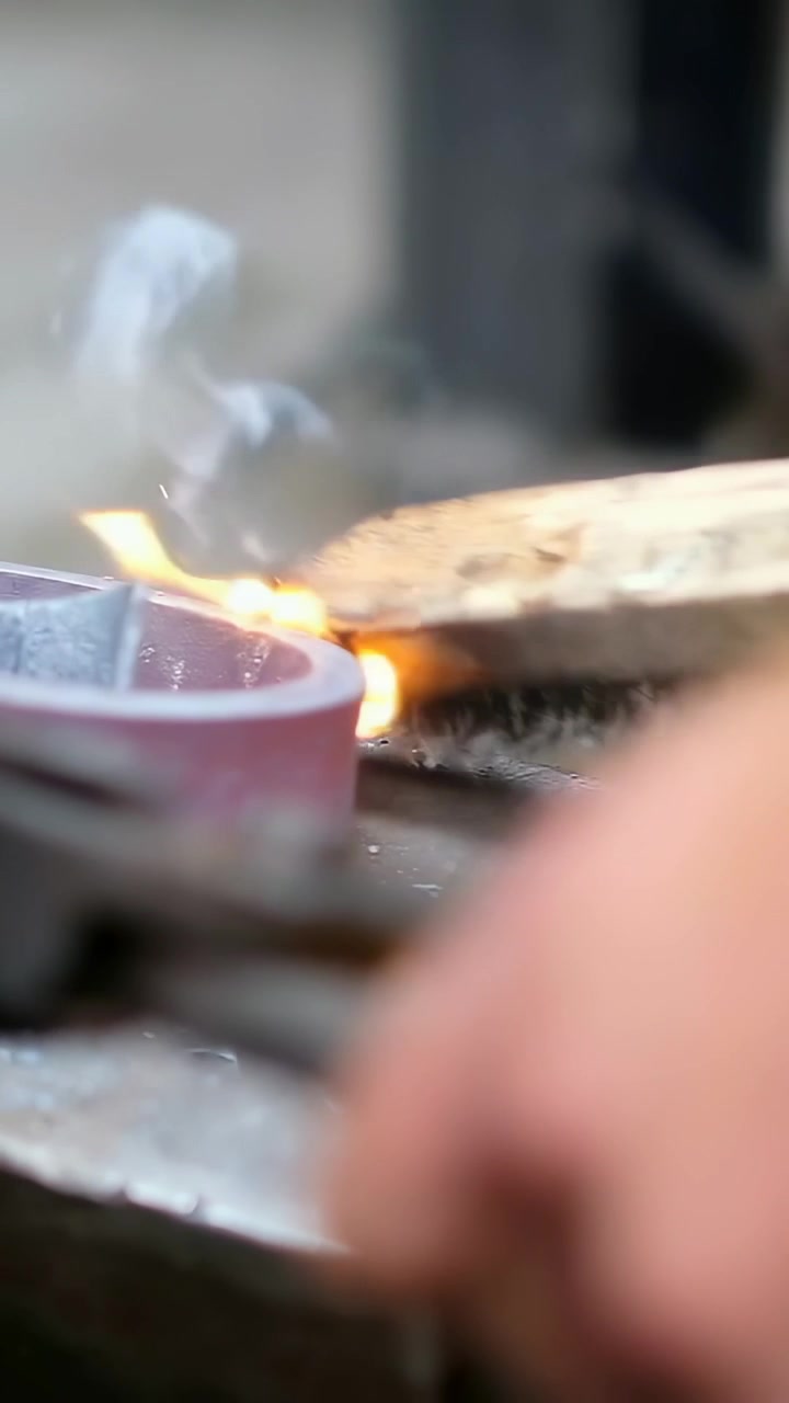 Vertical video: Positioning hand holding wire brush, cleaning red wheel at bench, sparking