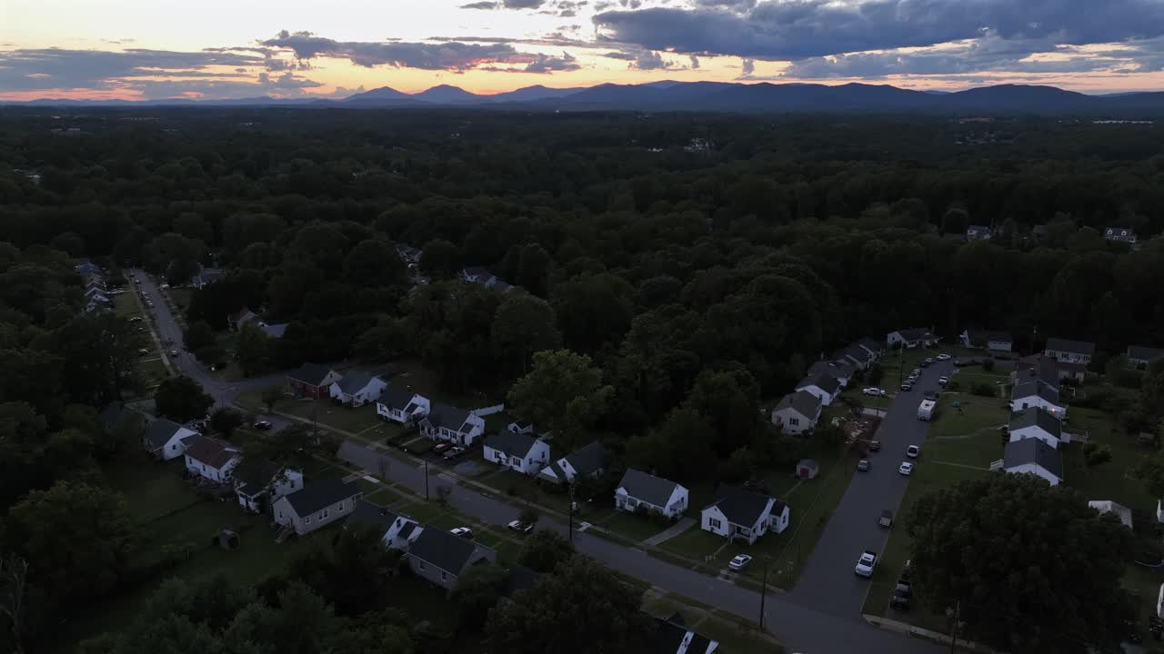 Quiet American suburb housing area with single family house between green trees at dusk. Descend aerial shot. Peaceful and quiet neighborhood in USA during summertime