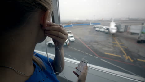 woman listening to music by the window at airport