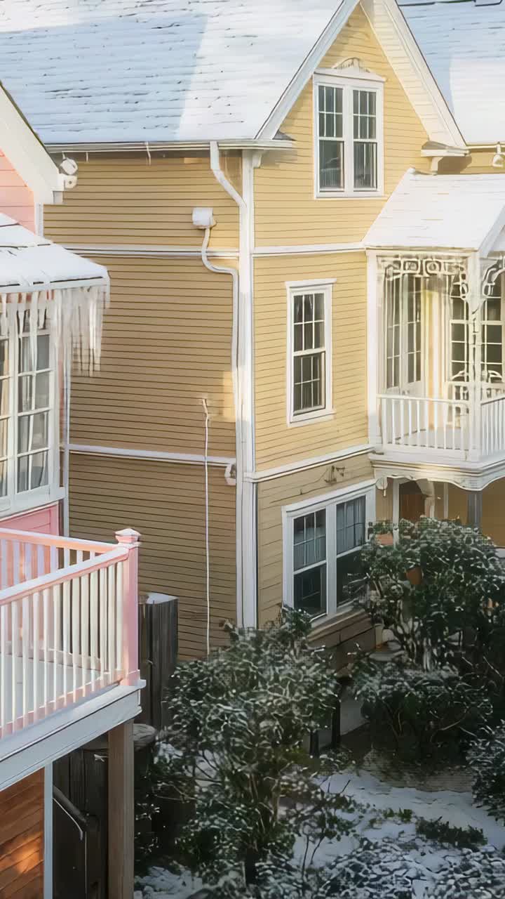 Vertikal video: Panorering med kamera, der afslører gul husfront i gård med pink balkon og istapper