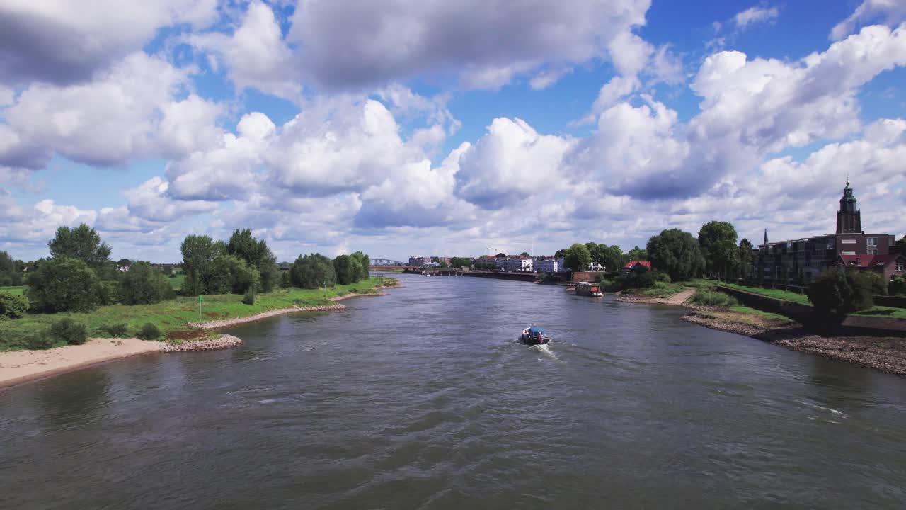 River IJssel passing Zutphen countenance seen from above against a blue vibrant colorful sky with IJsselkade quay and recreational port entrance visible in low water level