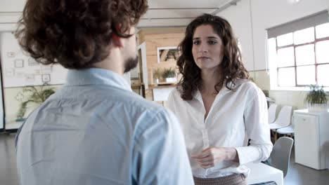 mujer joven pensativa hablando con un colega