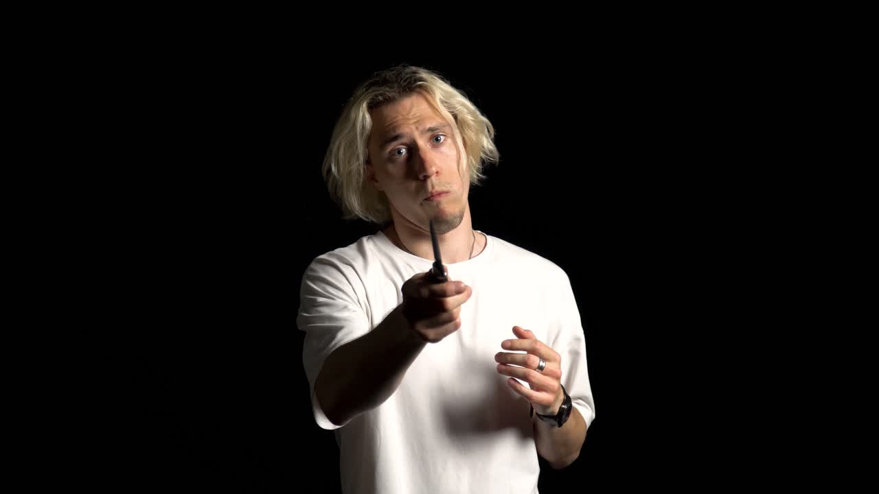 긴 머리카락의 금발 남자가 칼로 놀고 긴장하여 위협합니다.