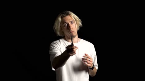 un hombre rubio de cabello largo jugando con un cuchillo y amenazando nerviosamente