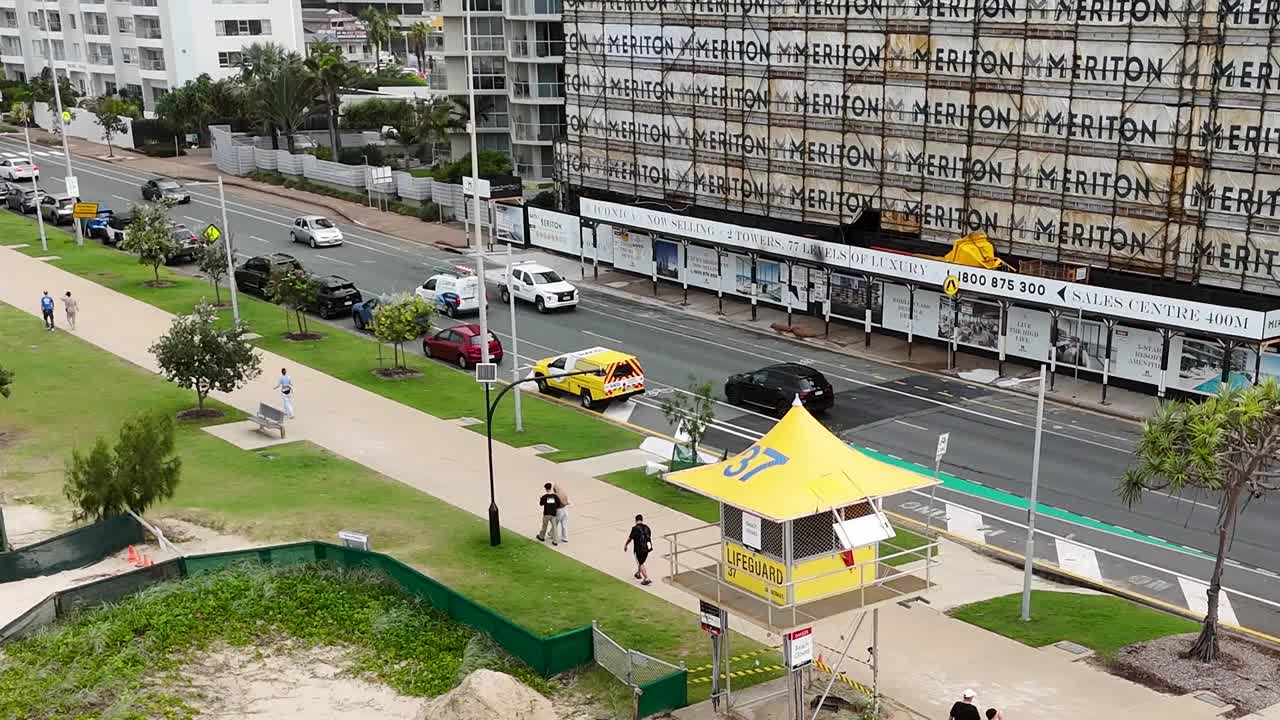 Vista en ángulo superior de una torre de salvavidas amarilla cerca de una carretera costera concurrida y edificios