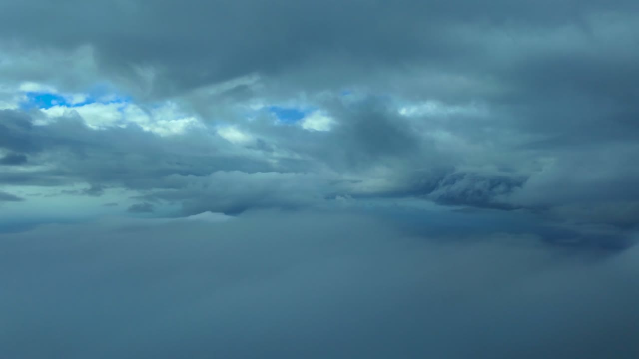A Pilot’s perspective from a jet airplane cockpit while flying at the blue hour between layers of broken cumulus and stratus clouds over the Mediterranean Sea