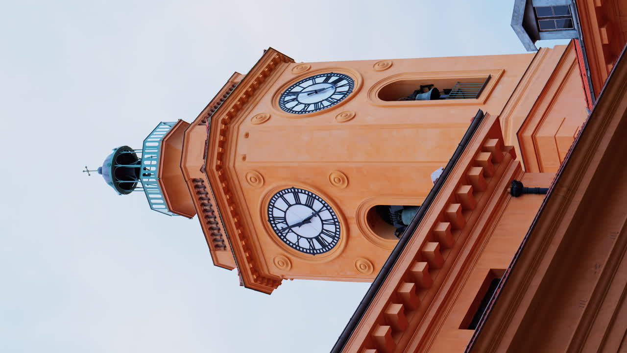 View of an orange clock tower in Nice, France with the sky on the background. Vertical