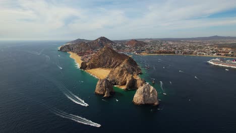 Aerial-view-of-boats-passing-the-rocky-peninsula-of-Cabo-San-Lucas,-sunny-Mexico