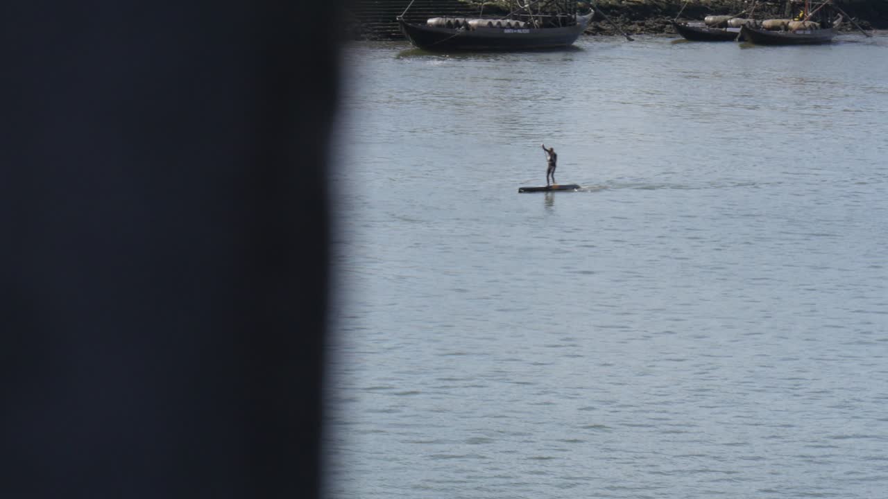 4k wide shot of man paddle boarding down river