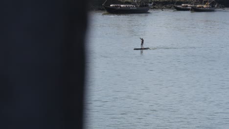 4k-wide-shot-of-man-paddle-boarding-down-river