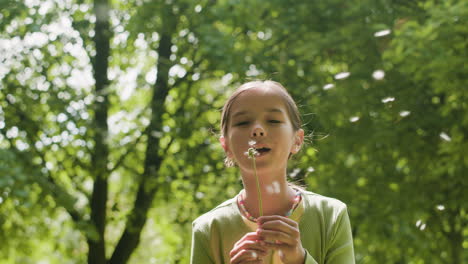 girl blowing dandelion seeds in nature