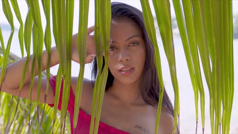 Enigmatic-young-woman-at-seashore-amid-green-plants