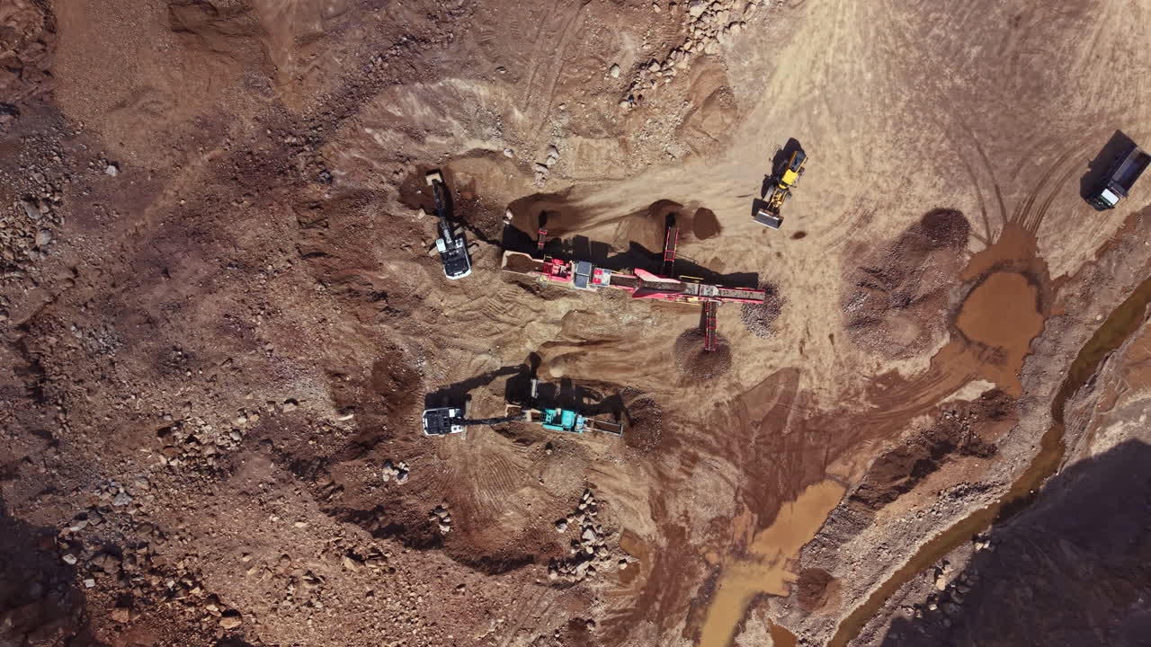 Construction equipment works on a site to move earth and prepare land for development in a dry area under clear skies