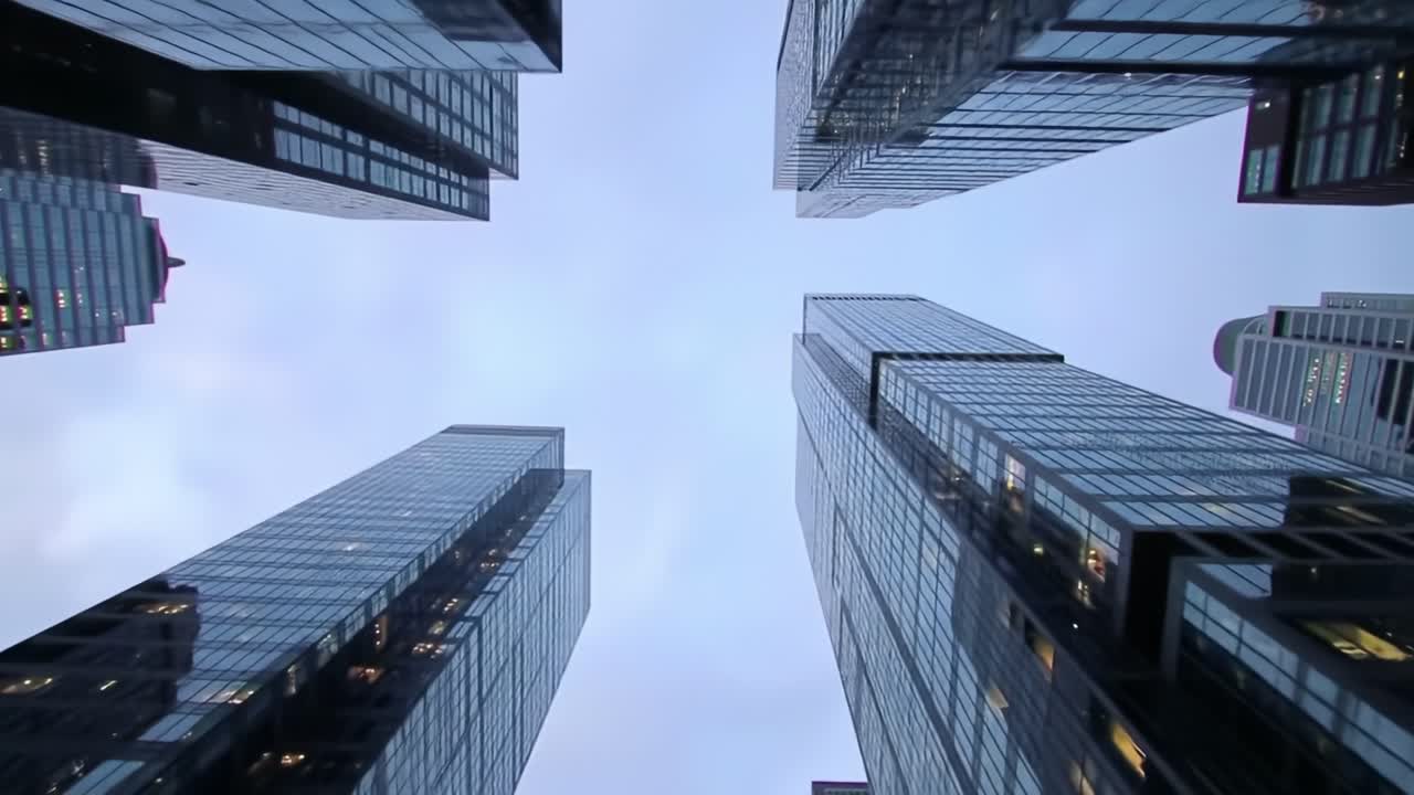 Buildings tower above as the day transitions to evening, with lights beginning to illuminate the cityscape. The perspective captures the essence of urban life and architecture.