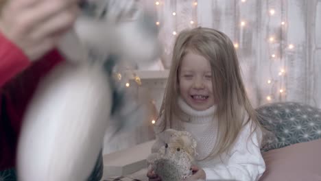 little-blond-girl-in-white-sweater-reacts-to-snow-globe-drop