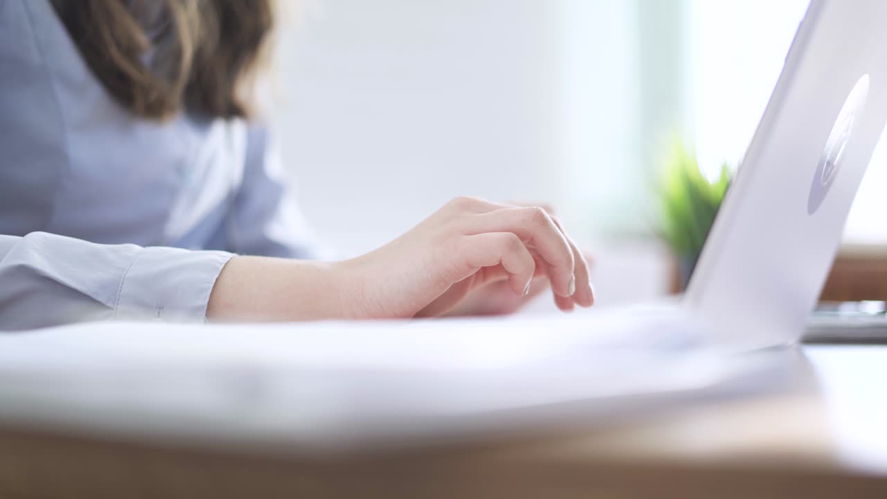 ラップトップのキーボードでタイプする女性の手