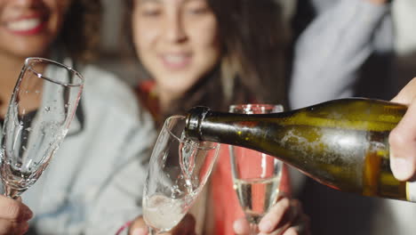 Close-up-of-mans-hand-pouring-champagne-into-glasses